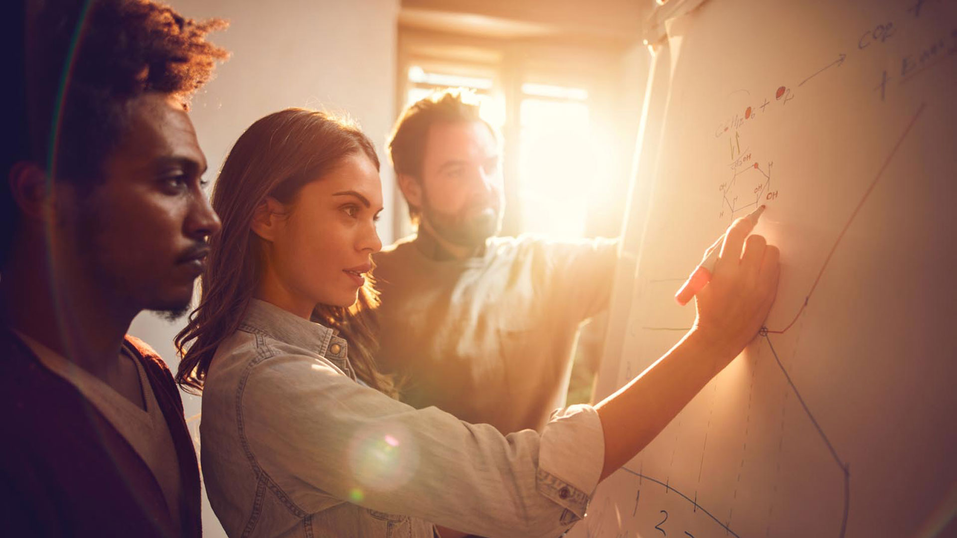 three-people-writing-on-a-white-board
