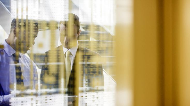 Two men talking through glass