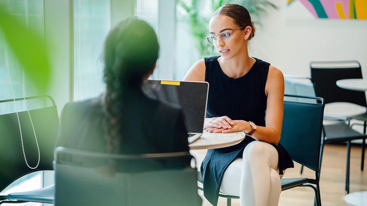 two woman talking with laptop