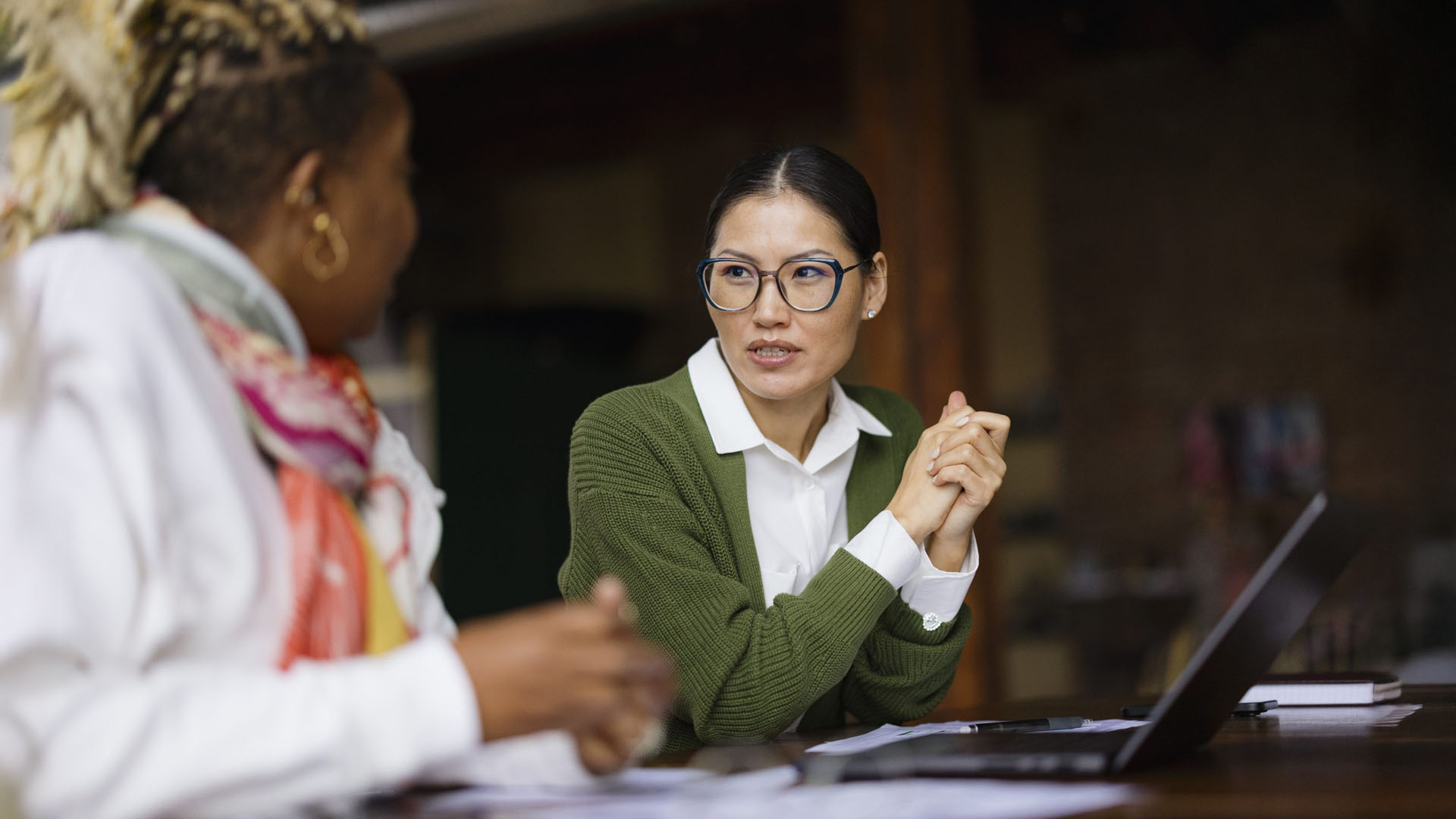 woman in green jumper talking in library