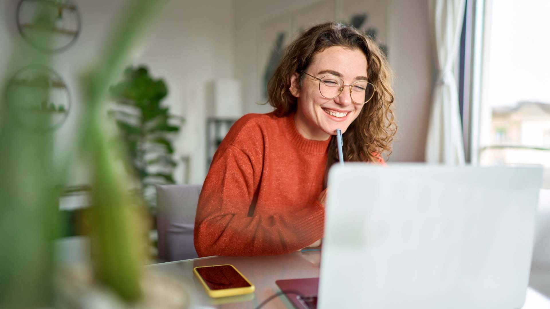 Woman in orange jumper in front of laptop