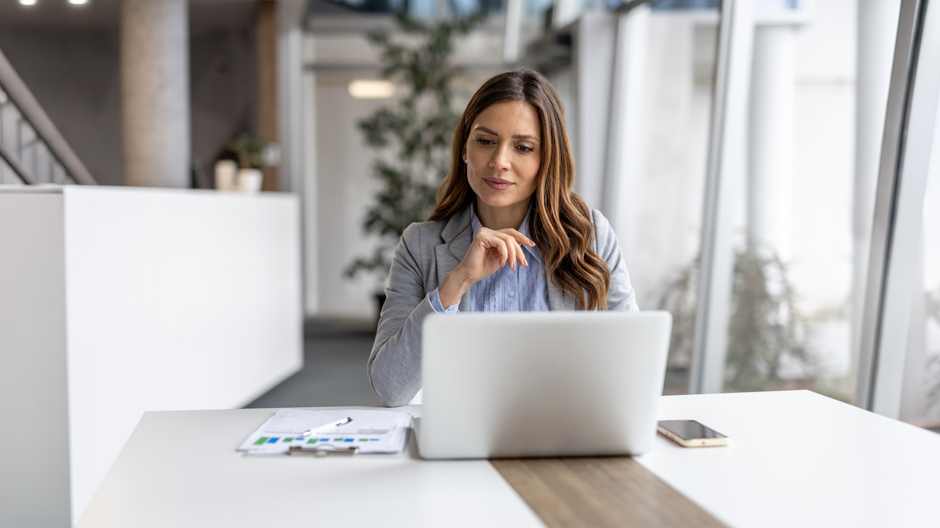 woman looking at laptop doing work on paper