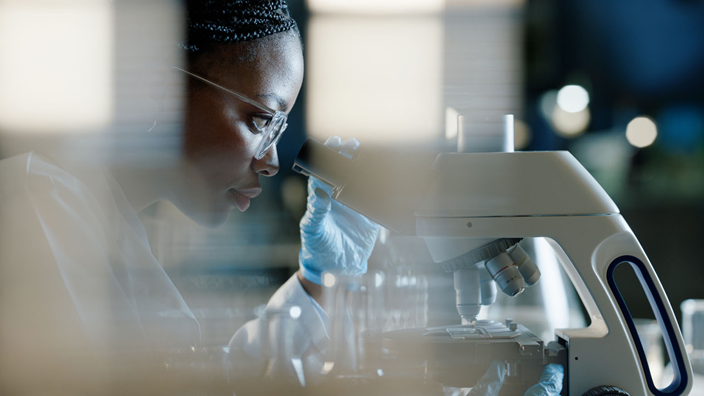 woman looking through a microscope in a laboratory