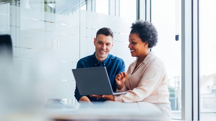 woman showing man something on laptop