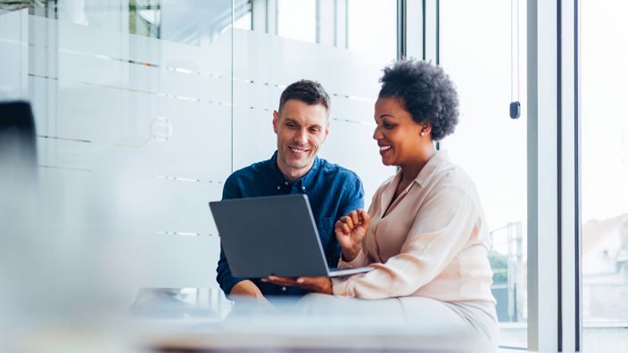 woman showing man something on laptop