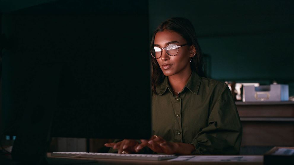 Woman typing on computer in the dark