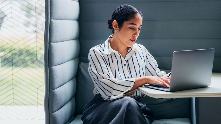Woman working on laptop in a booth