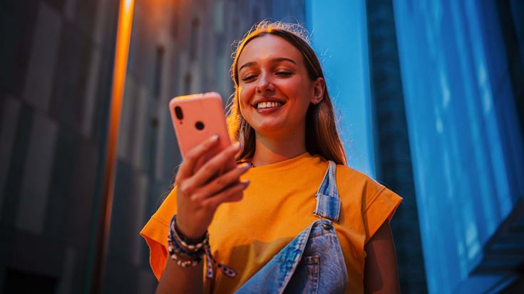 Young woman smiling at phone outside nighttime