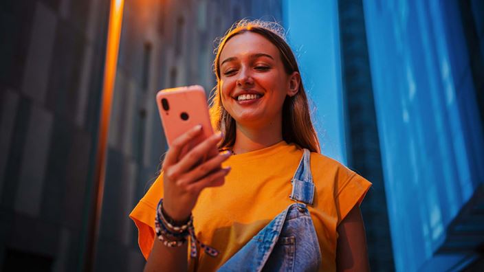 Young woman smiling at phone outside nighttime