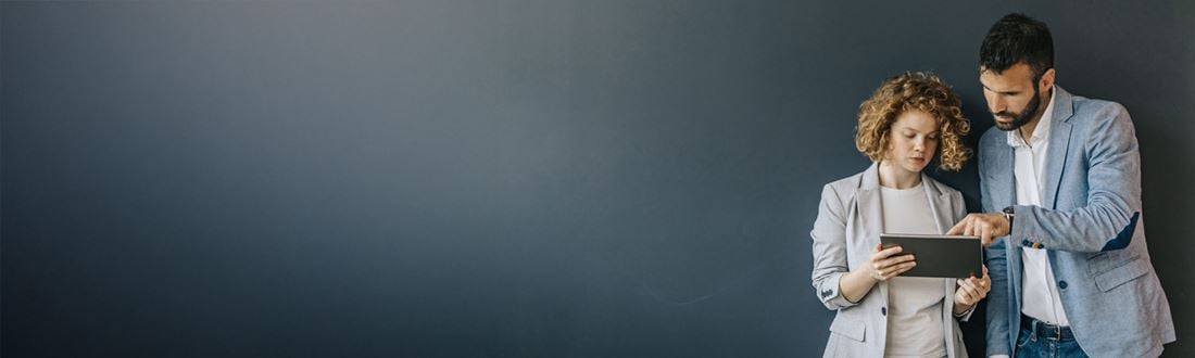 man and woman looking at tablet blue wall