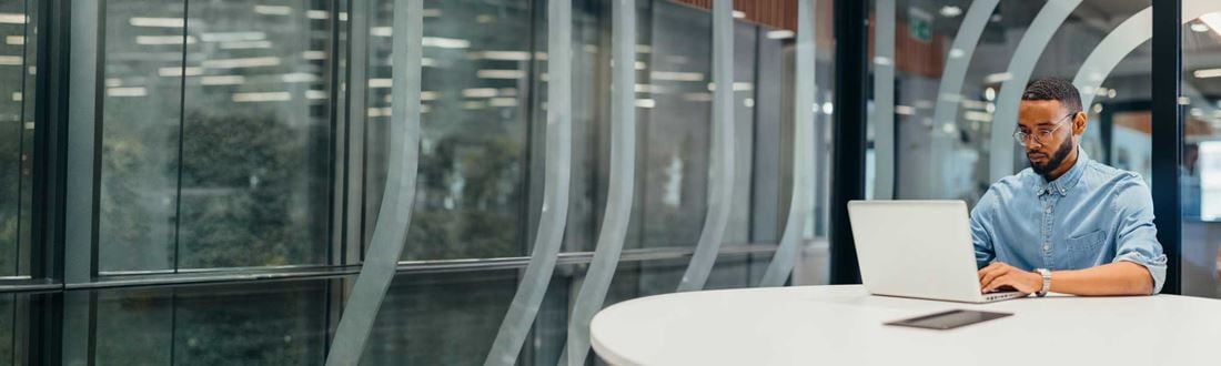 Man-typing-on-laptop-in-glass-office