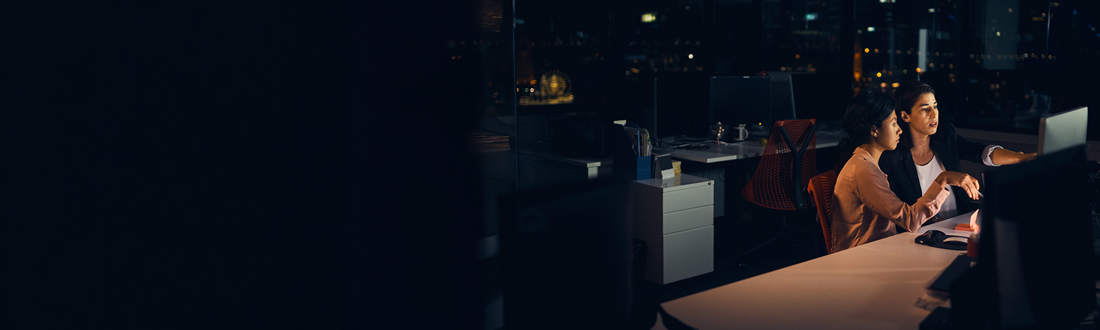 two women working on a computer at the night