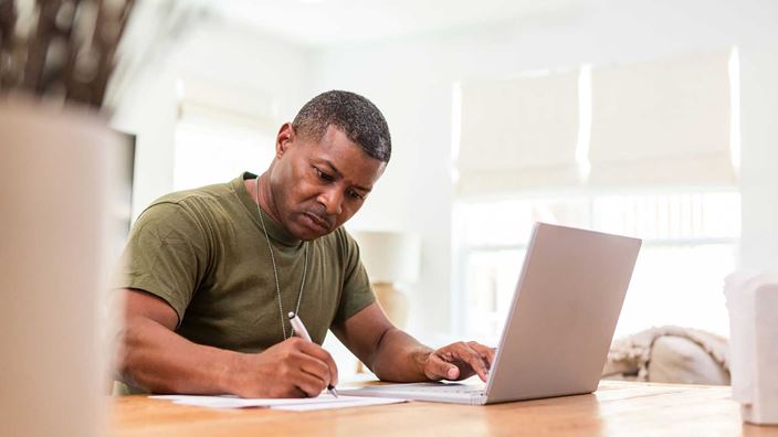 A man filling out paperwork at home