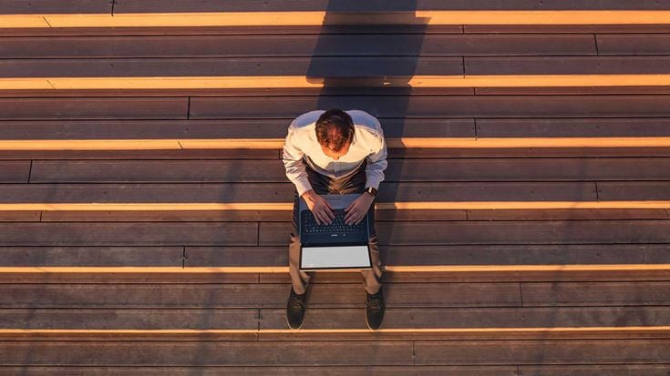 A professional on laptop on outdoor steps