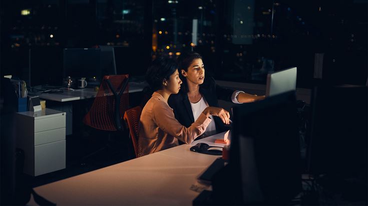 Two professionals working on computer data at night