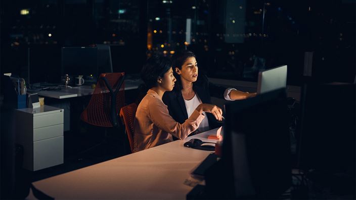 Two professionals working on computer data at night