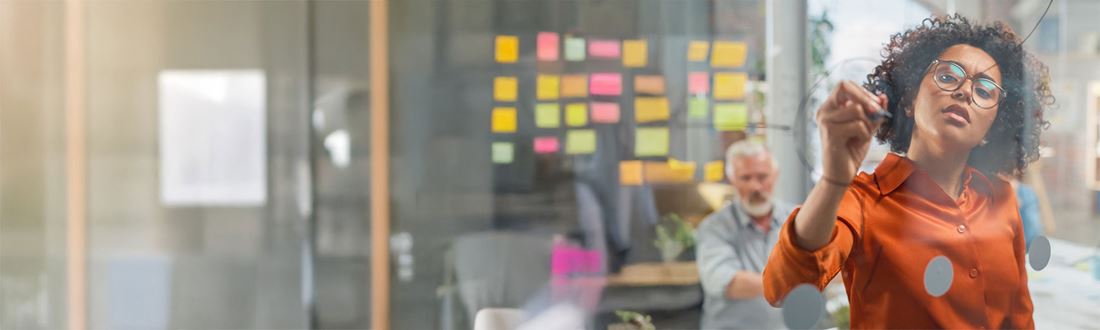 A professional woman writing on a board in a business meeting