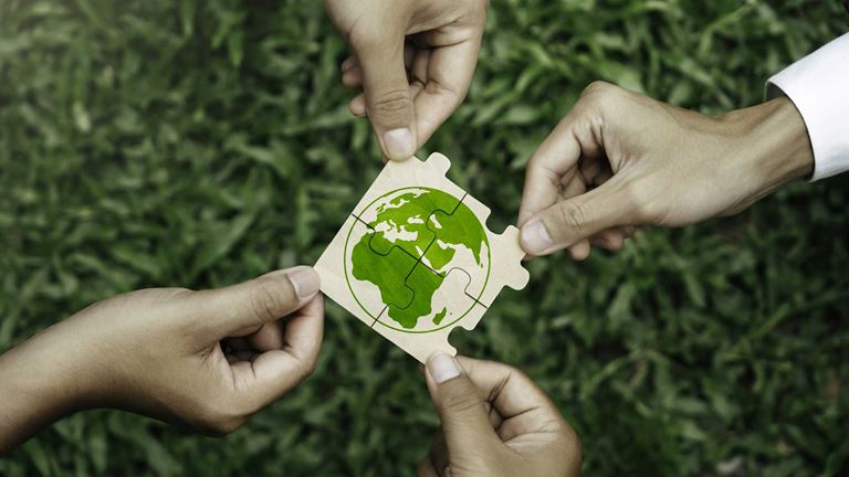 Hands holding puzzle pieces of a globe