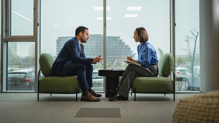 Man-and-lady-sitting-opposite-with-window-view