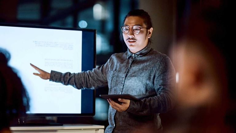 Man-pointing-at-screen-with-ipad-in-his-hand