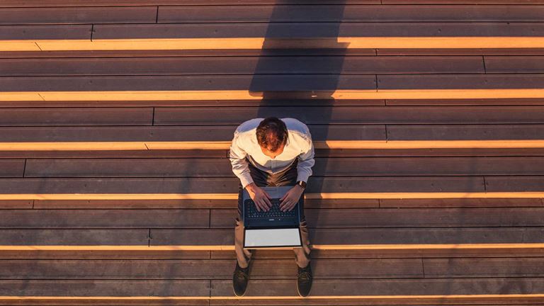 Man-sitting-on-steps-with-laptop-working