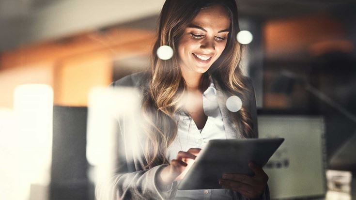 Woman-in-office-on-Ipad-tablet-smiling
