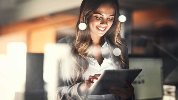 Woman-in-office-on-Ipad-tablet-smiling