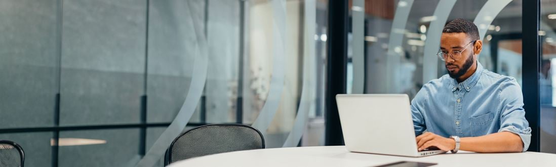 Man-working-in-office-with-glass-window-behind