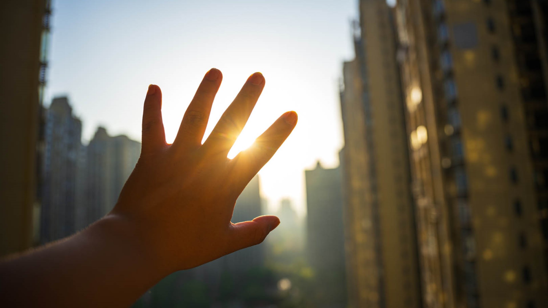 blocking sunlight with hand in city