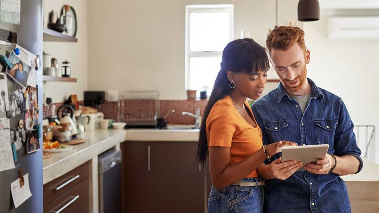 A couple using digital tablet to look over finances together