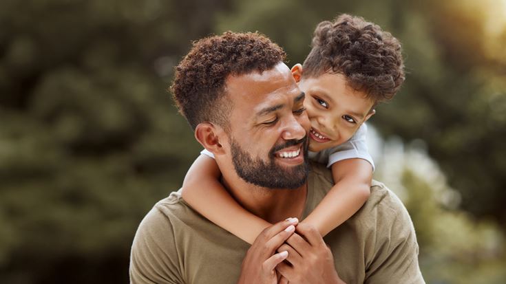 Man holding son over shoulders smiling