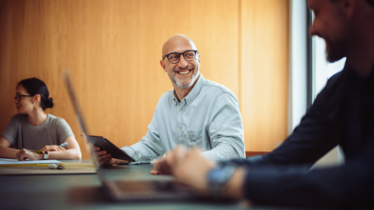 Man on tablet smiling at another person in the office