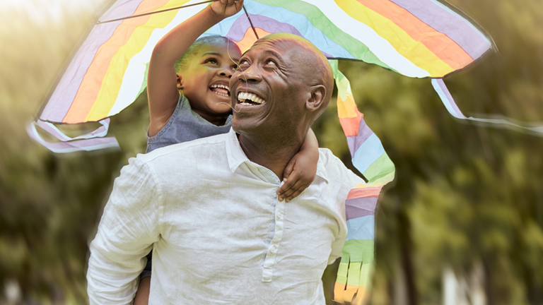 man with daughter on back flying a kite