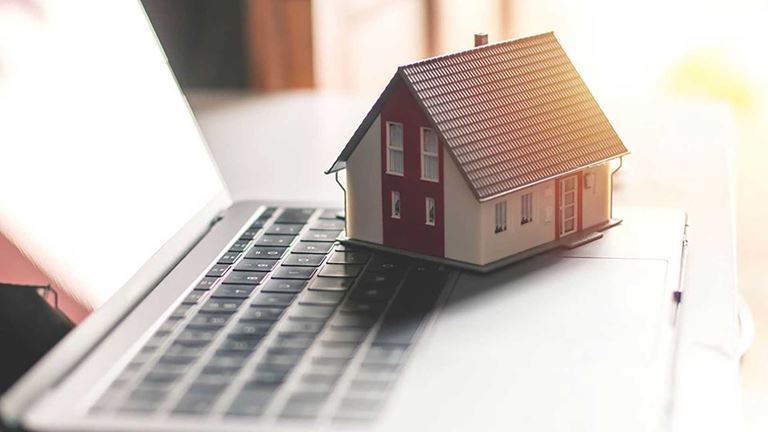 A miniature house sitting on a laptop