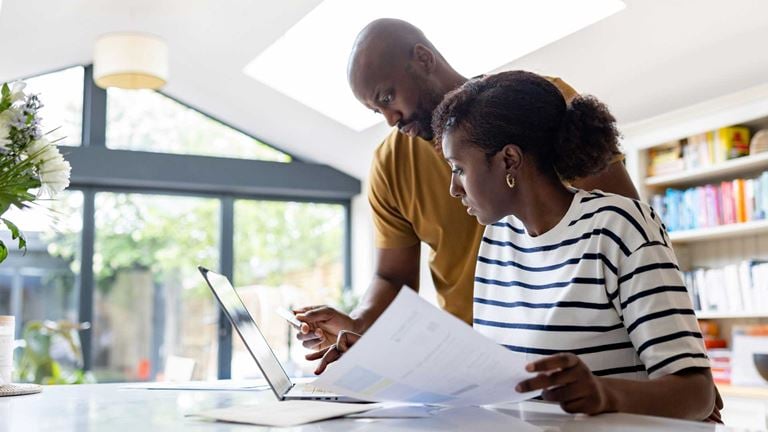 Two people working on laptop with paper