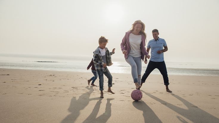 family playing football on the beach