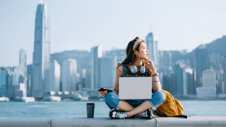 Woman sitting at riverside on laptop