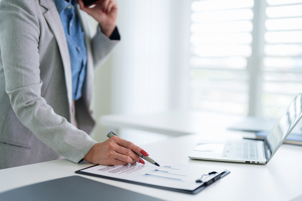 businesswoman analyzing financial report data chart graph document with pen at modern office desk