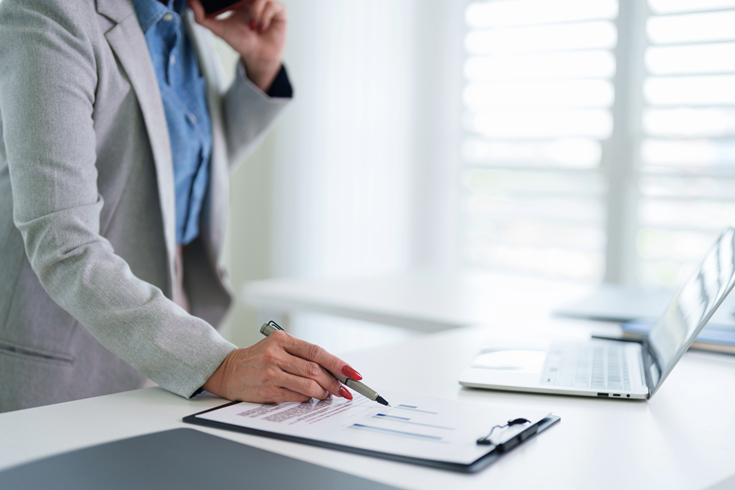 businesswoman analyzing financial report data chart graph document with pen at modern office desk