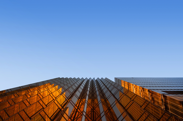 Modern corporate architecture in amber light against a clear blue sky, reflecting perspective and forward-looking decisions.