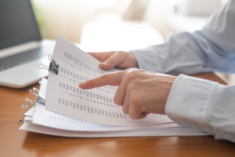 Persons hands pointing at numbers on a document reviewing financial reports