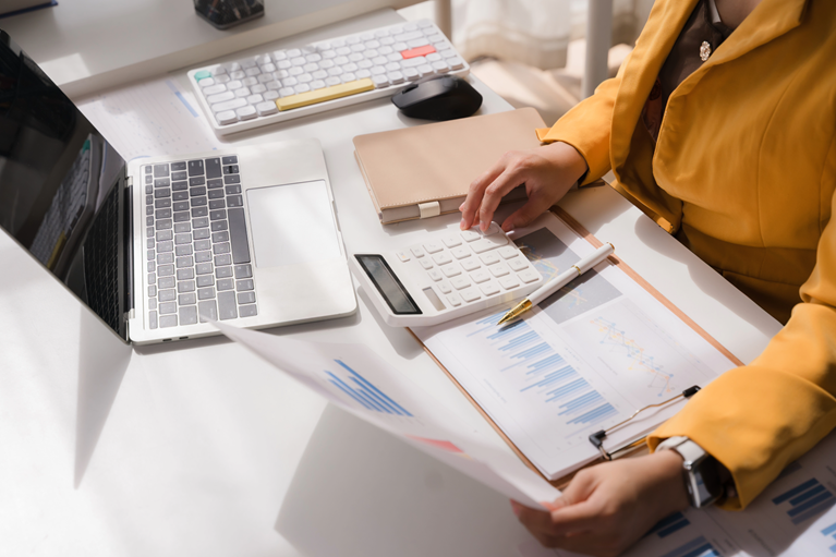 Professional Analysis A woman in a vibrant yellow blazer meticulously reviews financial reports